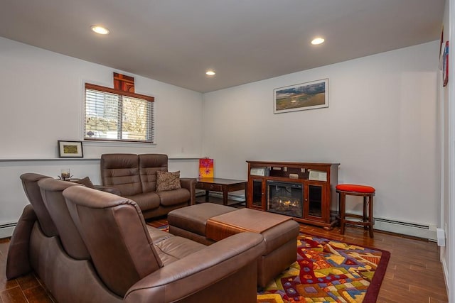 living room featuring a glass covered fireplace, recessed lighting, a baseboard heating unit, and wood finished floors