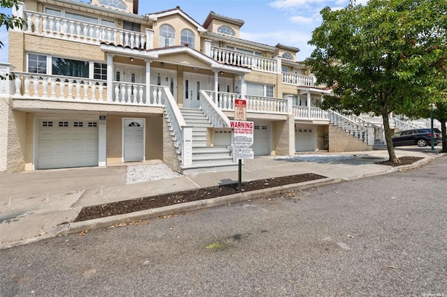 view of property with an attached garage, driveway, and stairway