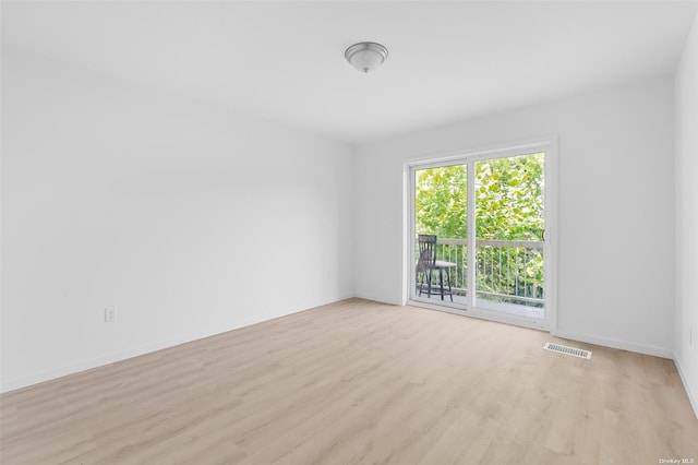 empty room with light wood finished floors, visible vents, and baseboards