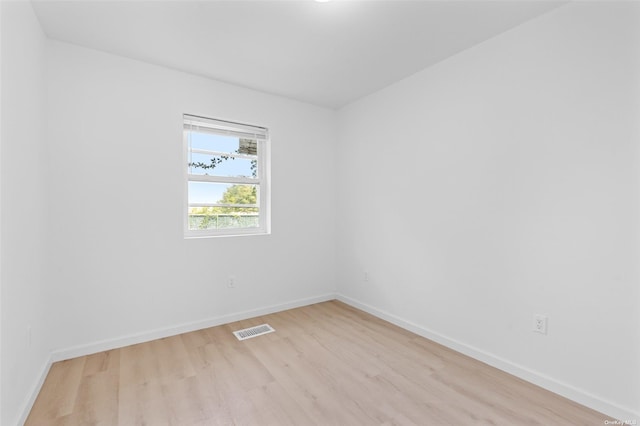 empty room with light wood-style floors, baseboards, and visible vents