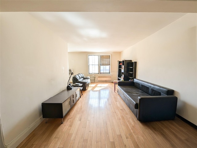 living area with light wood-style floors, radiator, and baseboards