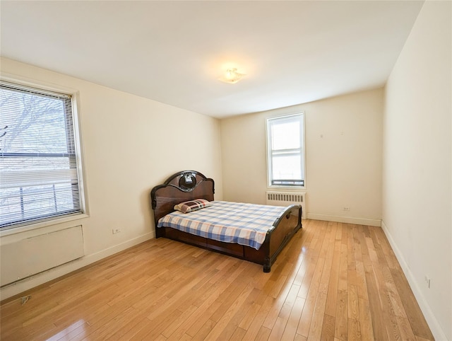 bedroom featuring light wood-type flooring, radiator, and baseboards