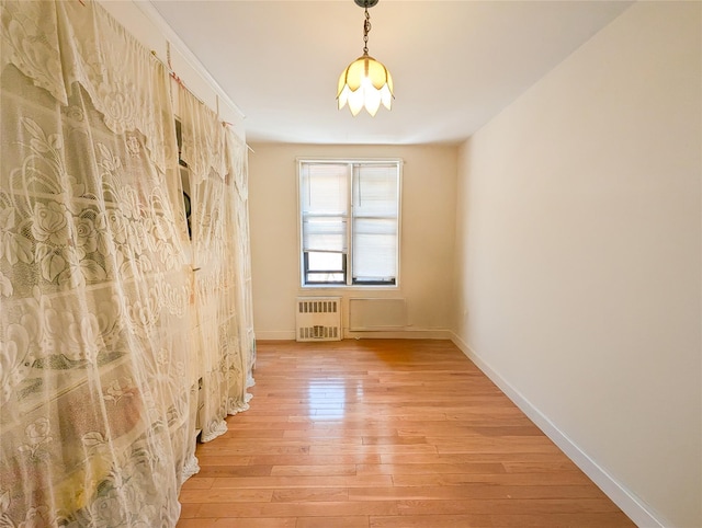 unfurnished room featuring light wood-type flooring, radiator heating unit, and baseboards