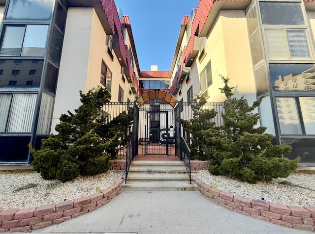 entrance to property with fence, a tile roof, a gate, and stucco siding