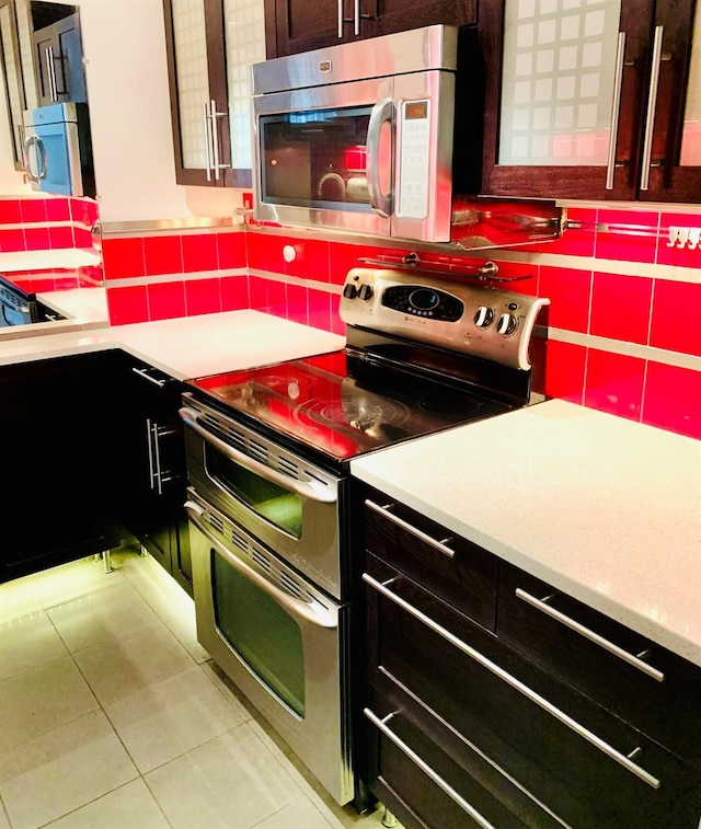 kitchen with light tile patterned floors, stainless steel appliances, backsplash, and light countertops