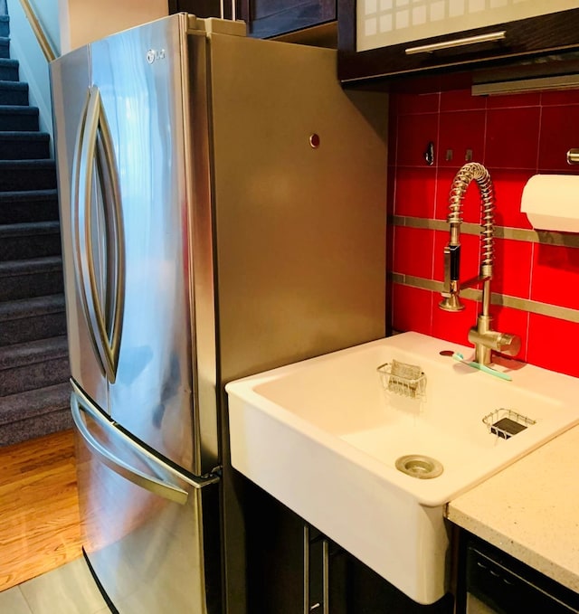 kitchen with tasteful backsplash, freestanding refrigerator, a sink, and wood finished floors