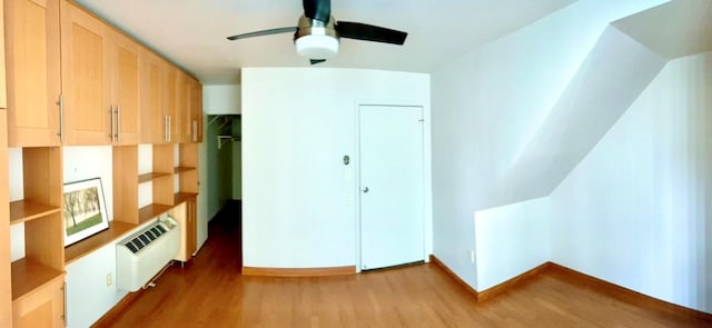 bonus room featuring a wall unit AC, a ceiling fan, baseboards, and wood finished floors