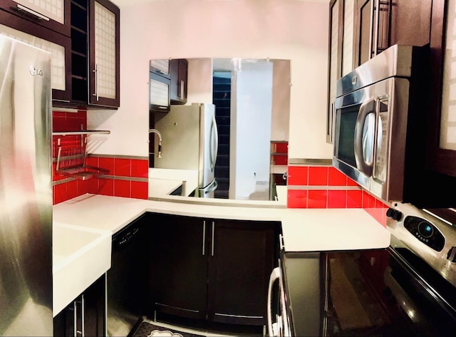 kitchen featuring appliances with stainless steel finishes, light countertops, glass insert cabinets, and decorative backsplash