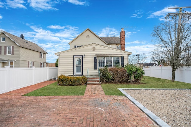 view of front of property featuring a front lawn, a chimney, and a fenced backyard