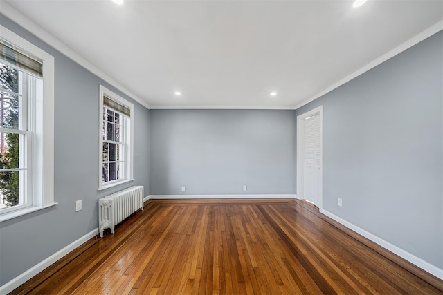 spare room with a healthy amount of sunlight, baseboards, radiator heating unit, and hardwood / wood-style flooring