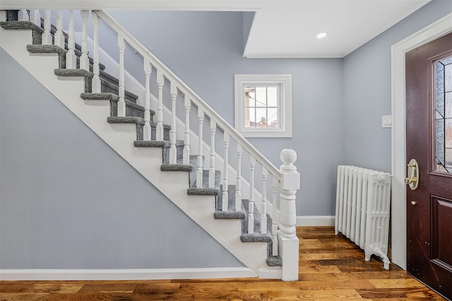 entryway featuring recessed lighting, wood finished floors, baseboards, stairs, and radiator