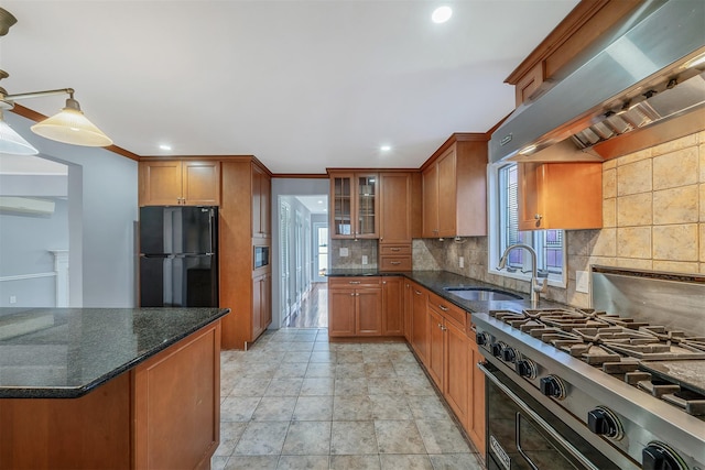 kitchen with brown cabinetry, freestanding refrigerator, gas stove, a sink, and ventilation hood