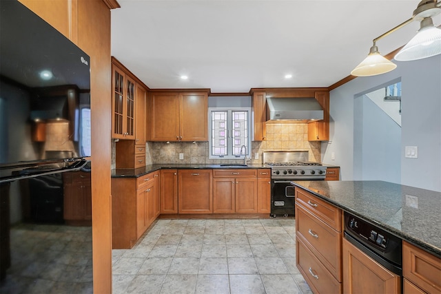 kitchen featuring brown cabinets, stainless steel range, tasteful backsplash, a sink, and wall chimney exhaust hood