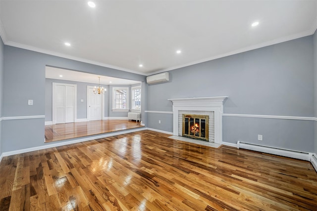 unfurnished living room featuring a baseboard heating unit, wood finished floors, ornamental molding, a brick fireplace, and an inviting chandelier