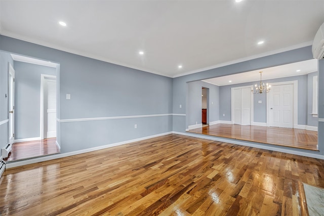 unfurnished living room with crown molding, baseboards, a chandelier, and wood finished floors