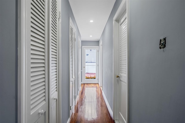 hallway with dark wood-type flooring, recessed lighting, and baseboards