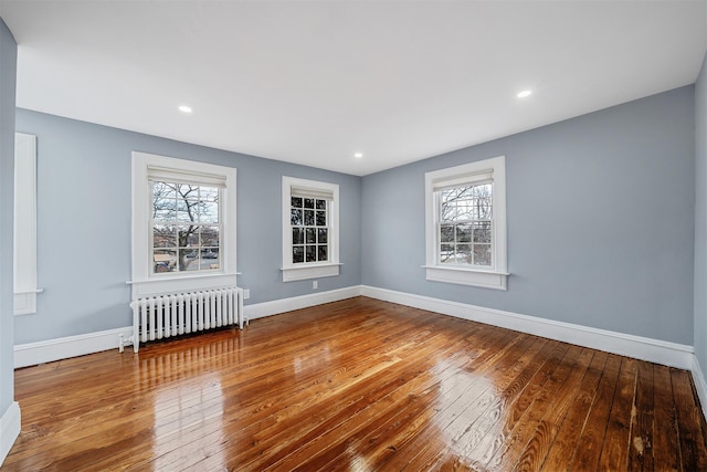 spare room featuring baseboards, hardwood / wood-style floors, recessed lighting, and radiator