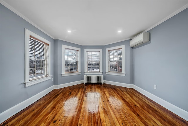 unfurnished room featuring baseboards, radiator, hardwood / wood-style floors, crown molding, and an AC wall unit