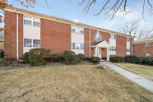 view of front of house featuring brick siding and a front yard