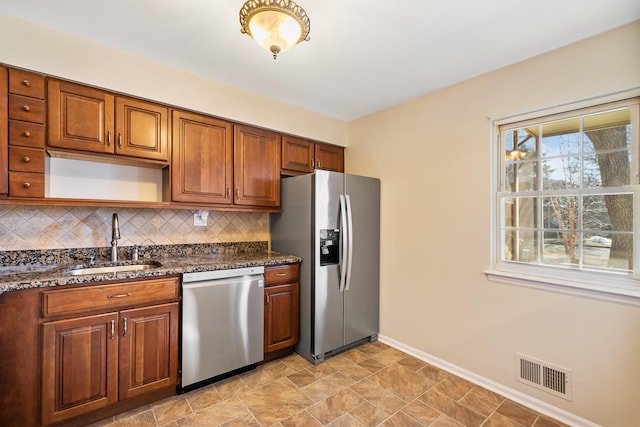 kitchen featuring brown cabinets, tasteful backsplash, visible vents, appliances with stainless steel finishes, and a sink