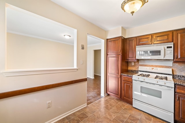 kitchen with crown molding, dark countertops, decorative backsplash, white appliances, and baseboards