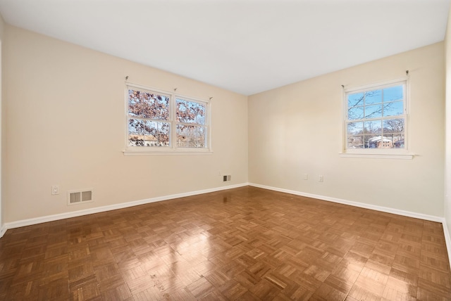 empty room featuring a healthy amount of sunlight, baseboards, and visible vents