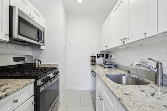 kitchen with backsplash, white cabinetry, stainless steel appliances, and a sink