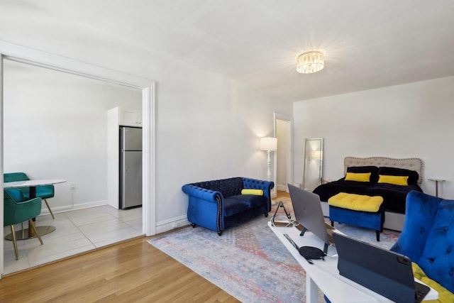 bedroom with baseboards, wood finished floors, and freestanding refrigerator