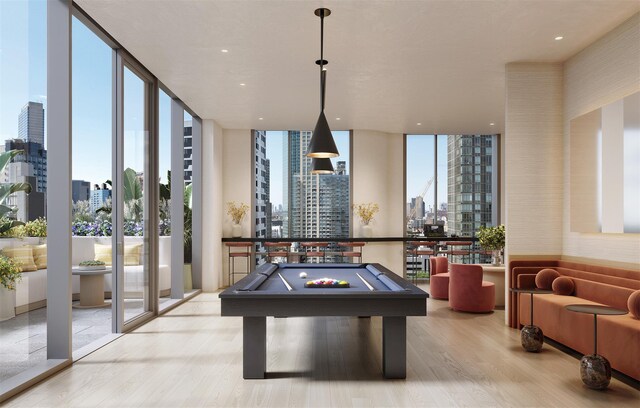 rec room featuring a view of city, pool table, wood finished floors, and floor to ceiling windows