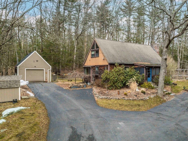 view of front facade with an outdoor structure, a detached garage, and a shingled roof