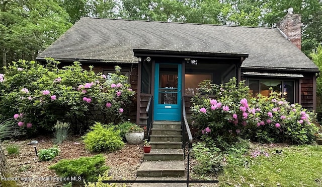 view of front of property with a chimney and a shingled roof