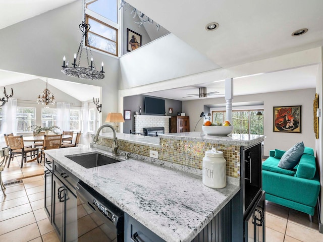 kitchen featuring a sink, open floor plan, light tile patterned floors, a brick fireplace, and dishwasher