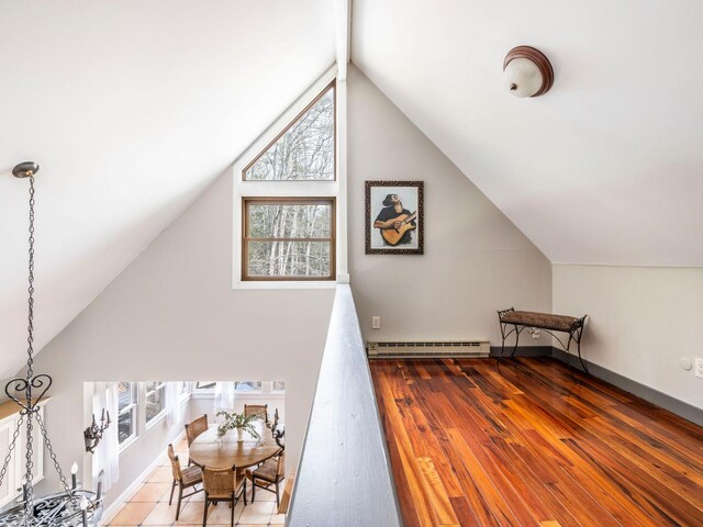 interior space with vaulted ceiling, a baseboard heating unit, baseboards, and hardwood / wood-style flooring