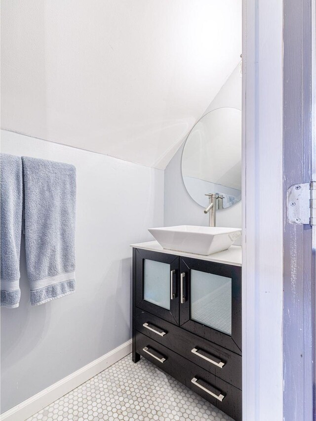 bathroom featuring vanity, vaulted ceiling, and baseboards