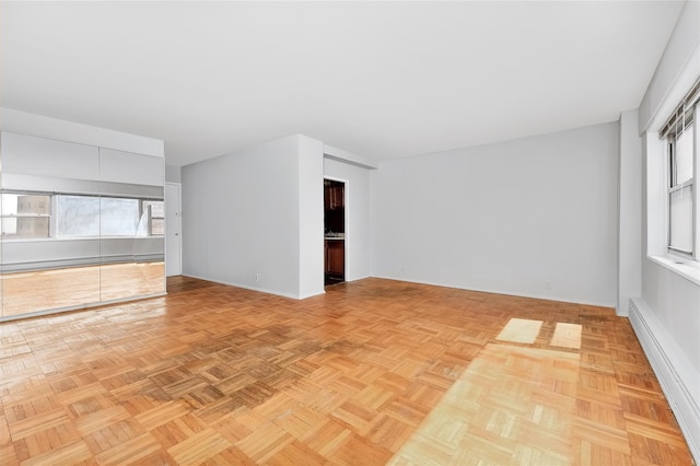 unfurnished room with a wealth of natural light and baseboard heating