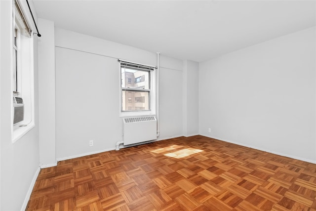 unfurnished room with baseboards, cooling unit, and radiator