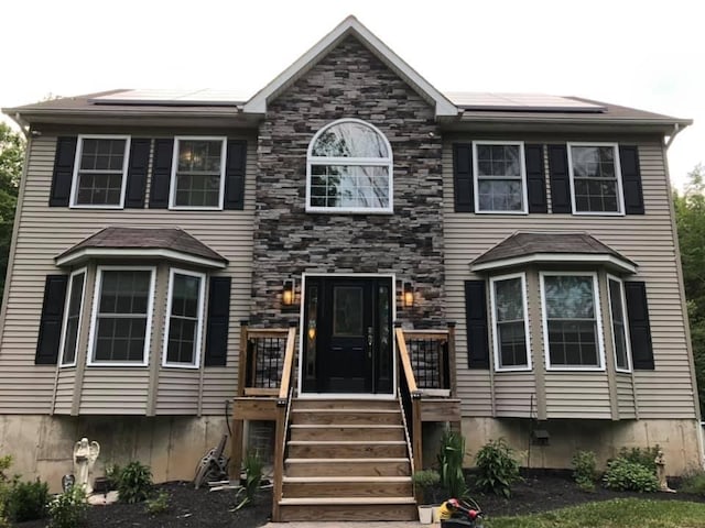 view of front of house featuring stone siding and roof mounted solar panels