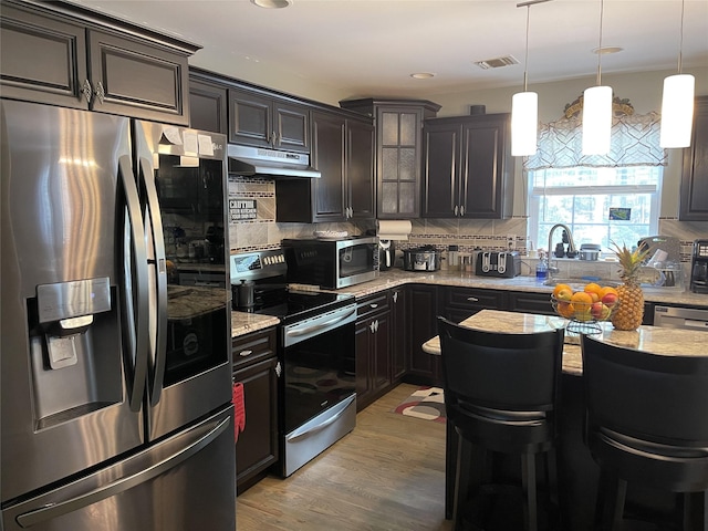 kitchen featuring visible vents, decorative backsplash, light wood-style flooring, appliances with stainless steel finishes, and under cabinet range hood