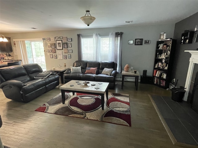 living area with visible vents, a fireplace with raised hearth, and dark wood finished floors