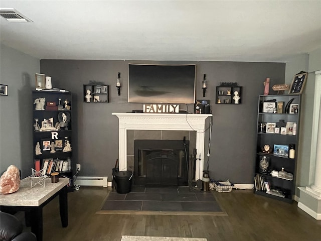 living room featuring a baseboard heating unit, visible vents, a tiled fireplace, and wood finished floors