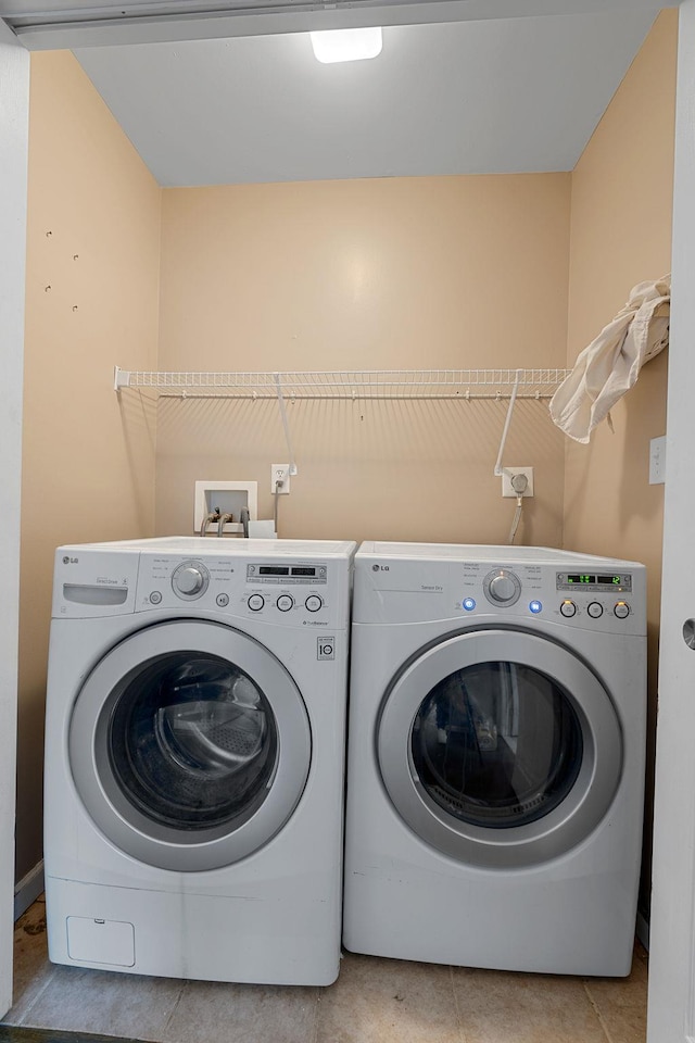 laundry room featuring light tile patterned floors, laundry area, and independent washer and dryer