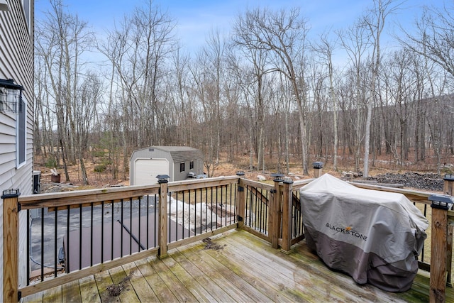 wooden deck with an outbuilding, area for grilling, a view of trees, and a detached garage
