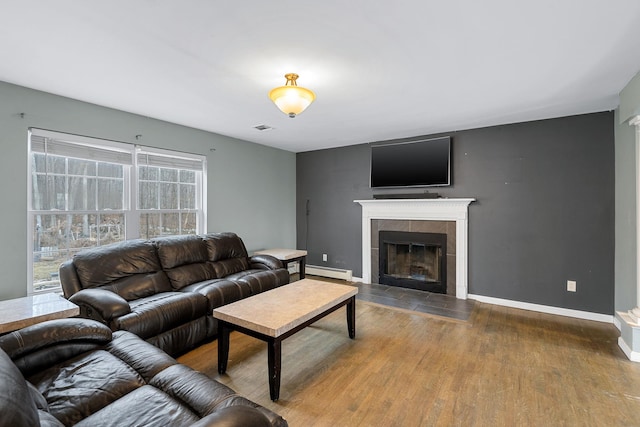 living room with wood finished floors, baseboards, visible vents, a baseboard radiator, and a tile fireplace
