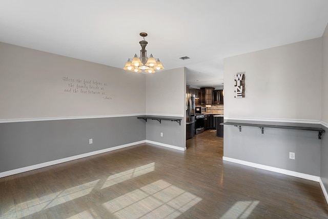 interior space featuring visible vents, baseboards, an inviting chandelier, and dark wood-style flooring