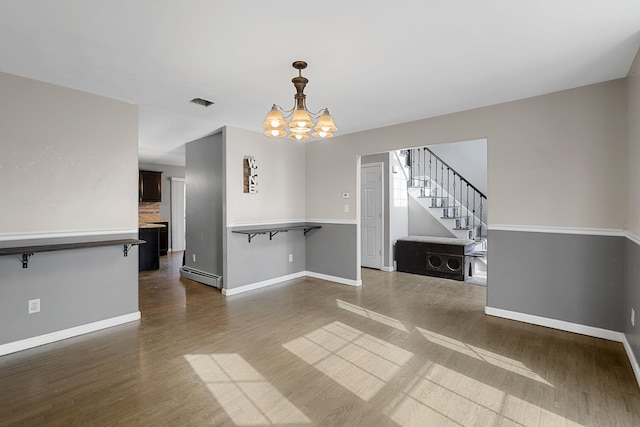 unfurnished dining area with a baseboard heating unit, an inviting chandelier, baseboards, and dark wood-type flooring