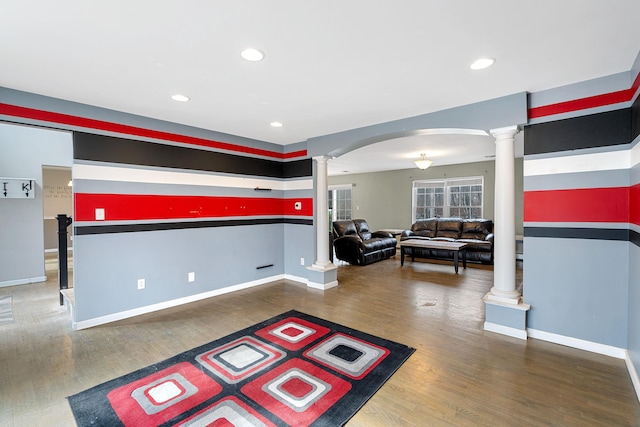 interior space featuring decorative columns, wood finished floors, arched walkways, and baseboards