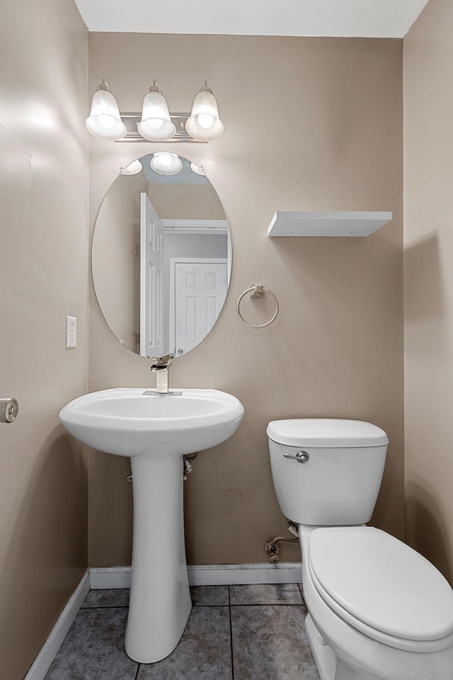 bathroom featuring tile patterned floors, toilet, baseboards, and a sink