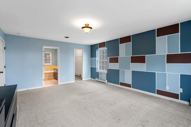 unfurnished bedroom with visible vents, carpet flooring, baseboards, baseboard heating, and a spacious closet