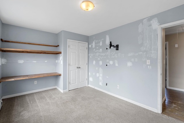 unfurnished bedroom featuring a closet, baseboards, attic access, and carpet flooring