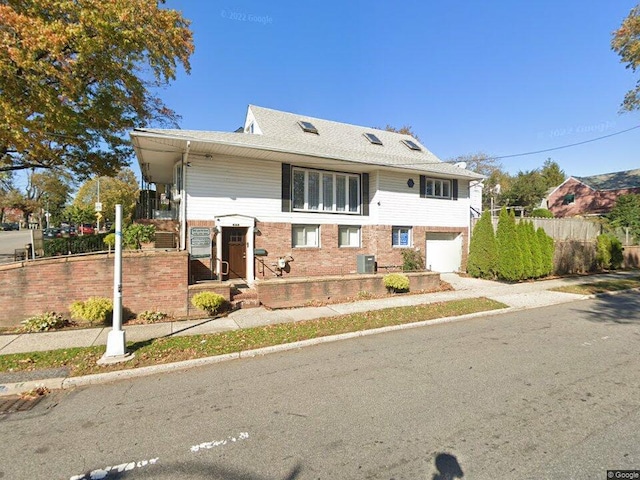 view of front of property with brick siding, fence, an attached garage, and central air condition unit